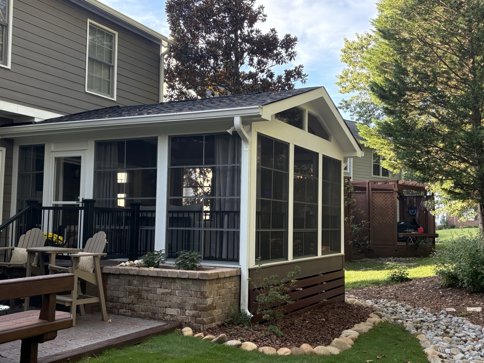 A screened porch on a stone-veneer base with a paver landing and river-rock border — the kind of detail our reviewers call out.