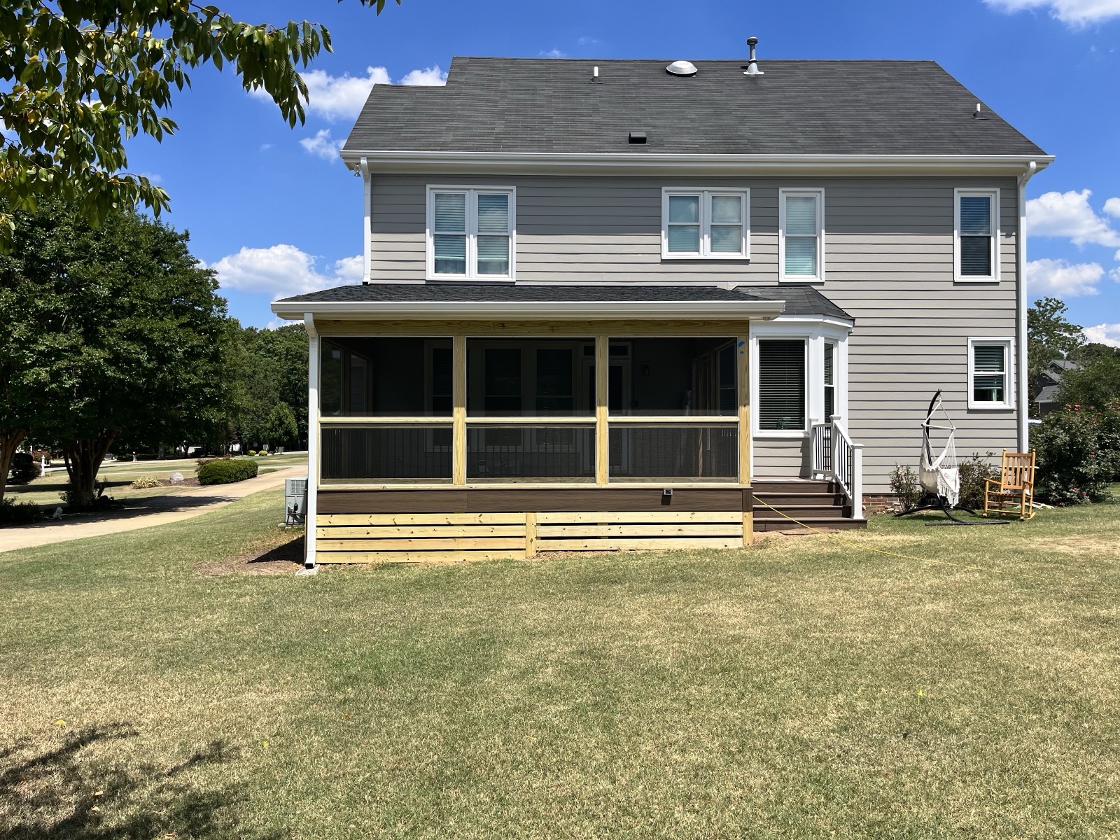 A rear-of-home screened porch with clean framing and a fresh natural-wood finish, ready for its first Carolina summer.